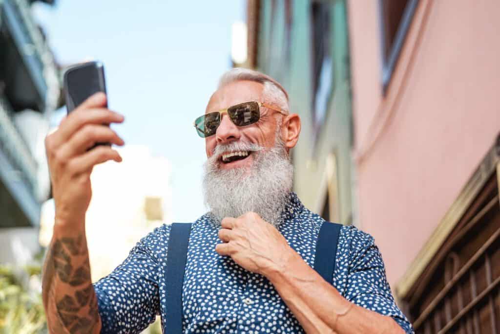 Bearded senior using mobile phone outdoor - Hipster mature man h