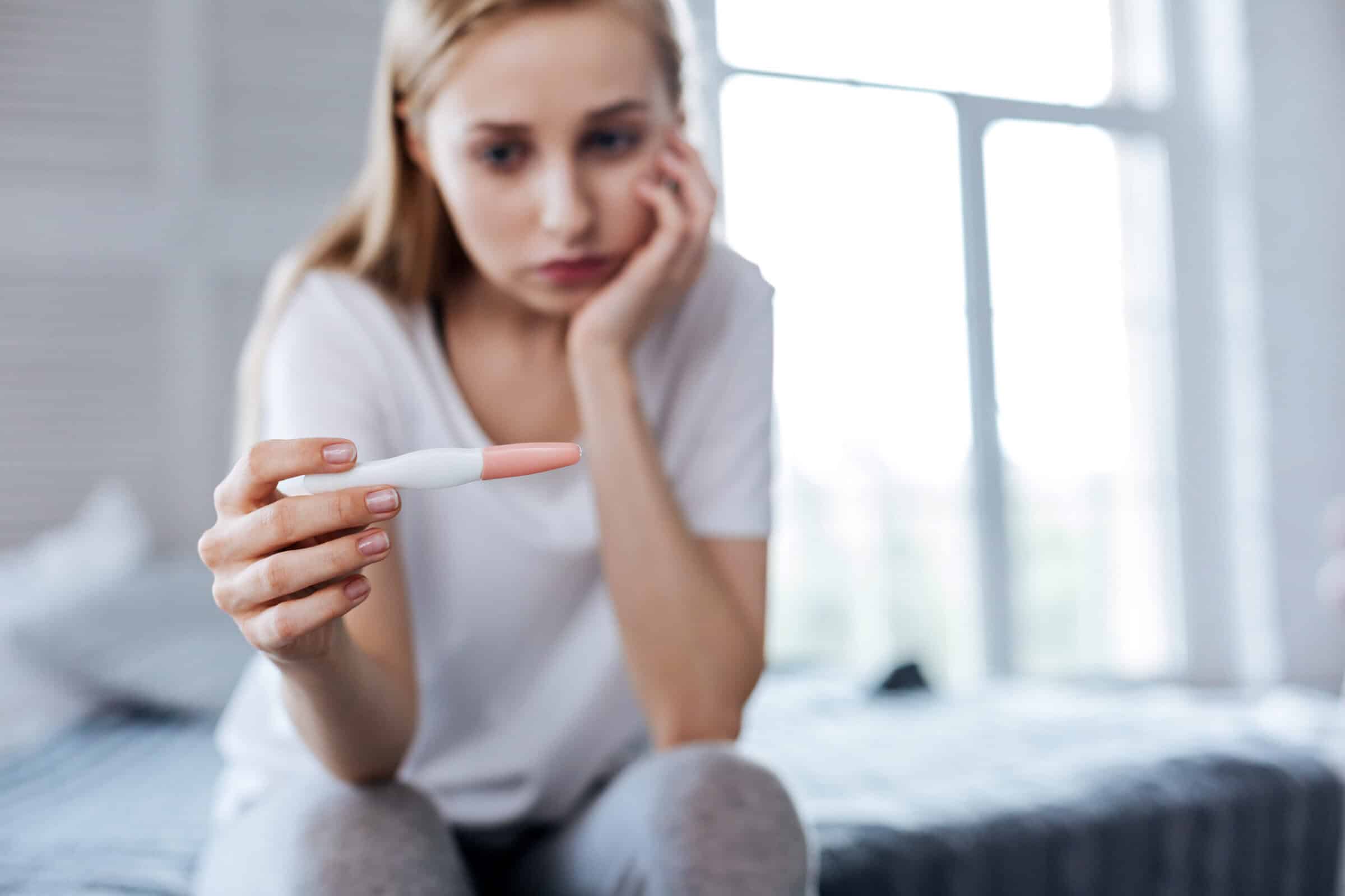 Sad woman holding her pregnancy test